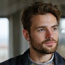 Retrato de un hombre joven con una barba cuidada y una expresión pensativa, indicando introspección y bienestar.